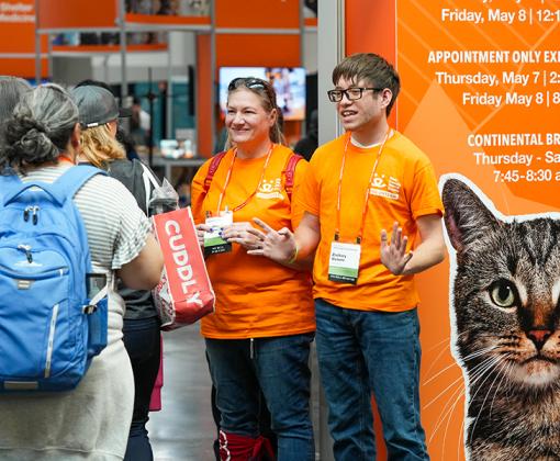 Best Friends volunteers talking with 2026 Best Friends National Conference attendees beside signage with a cat