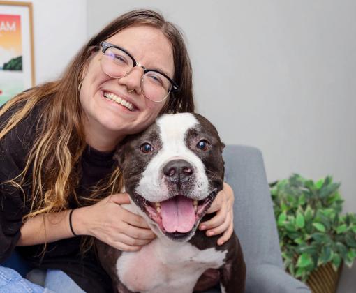 Smiling person hugging a black and white dog