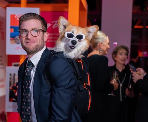 Volunteer Bryan Reisberg with a dog wearing sunglasses in a backpack