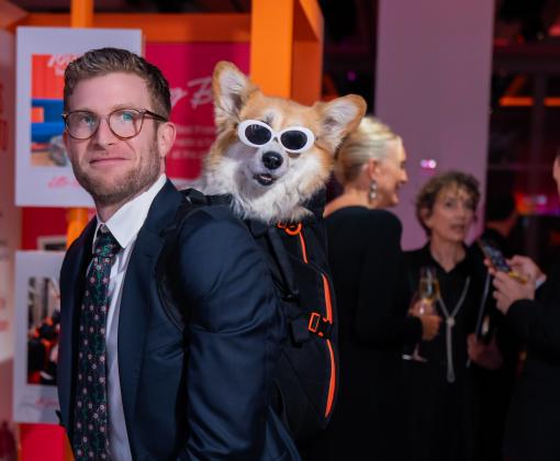 Volunteer Bryan Reisberg with a dog wearing sunglasses in a backpack