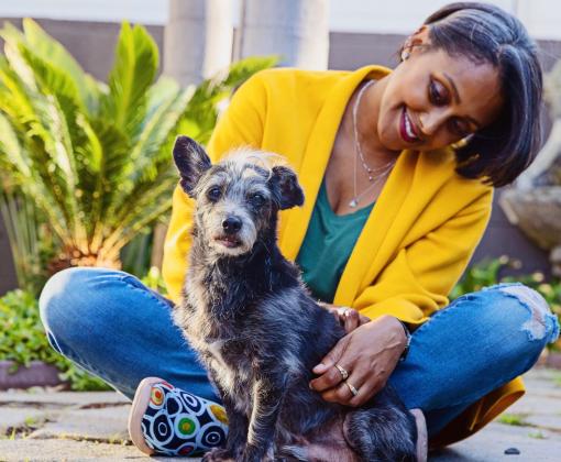 Smiling person sitting with a small dog outside