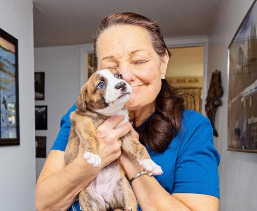 Smiling person holding and snuggling a puppy