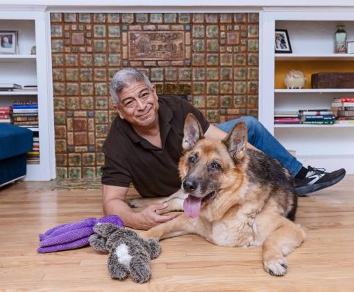 Person on the floor with his shepherd with some dog toys