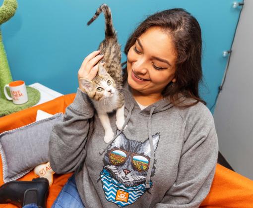 Smiling person wearing a Best Friends sweatshirt with a kitten on her shoulder