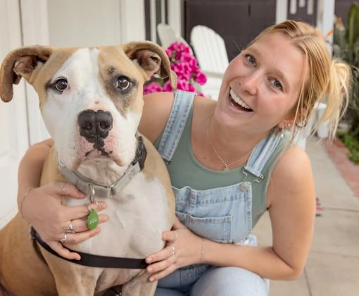 Smiling person sitting on a patio with a dog next to them