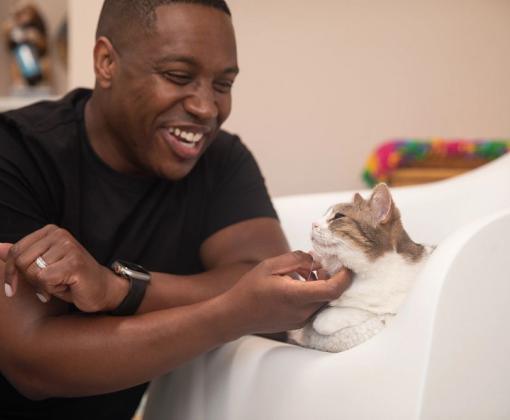 Man in black shirt stroking chin of cat