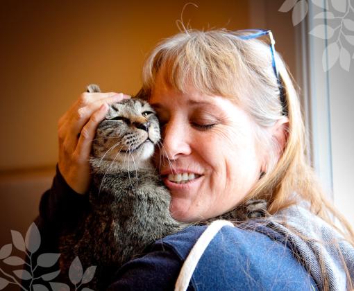 woman snuggling face-to-face with brown tabby cat