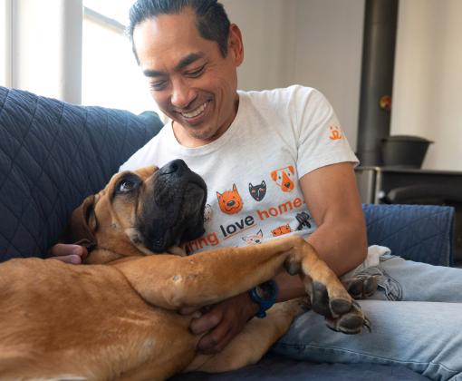 Smiling person sitting with a large dog on a couch in a home environment