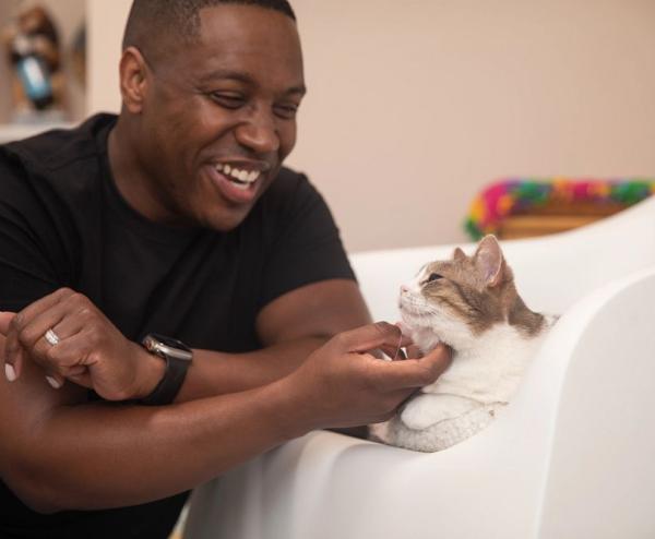Man in black shirt stroking chin of cat