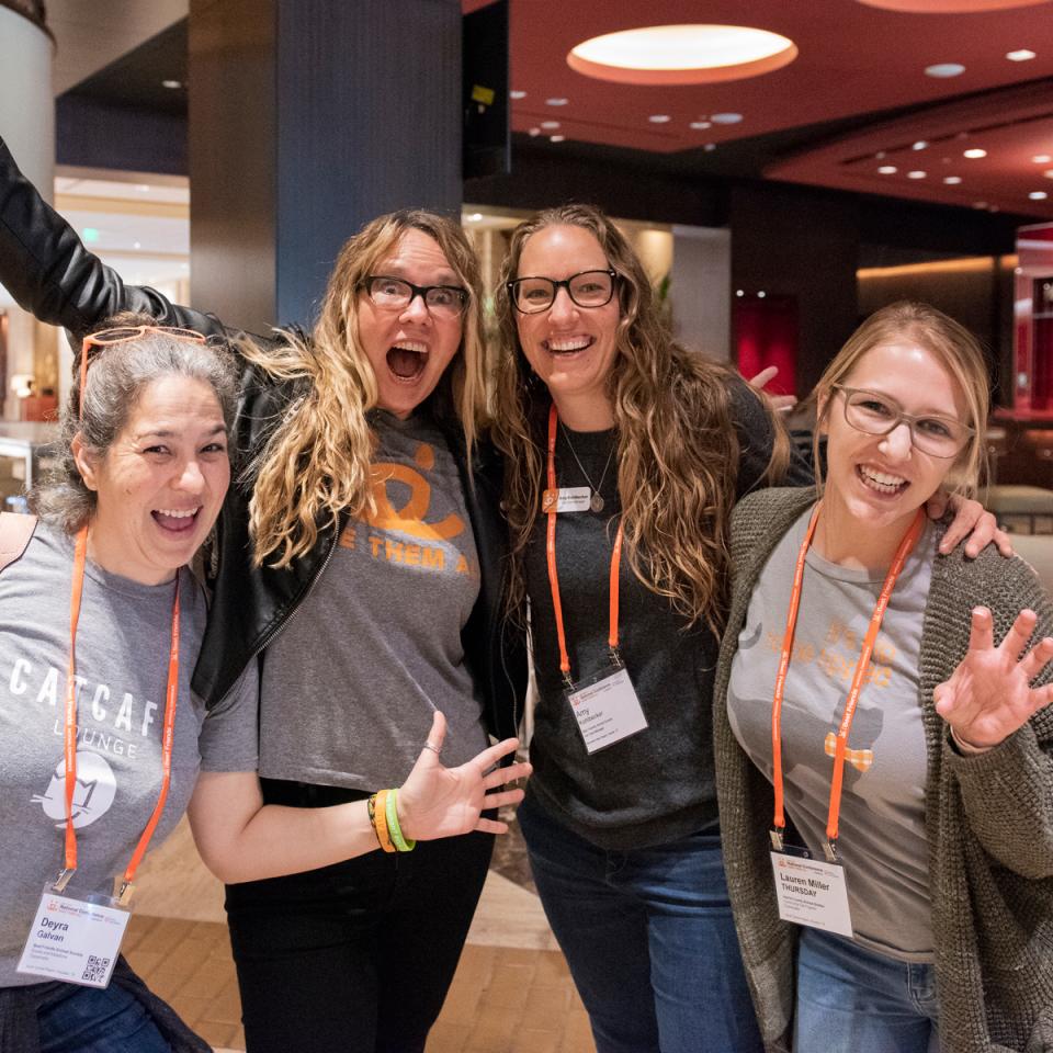 Four women cheering at conference