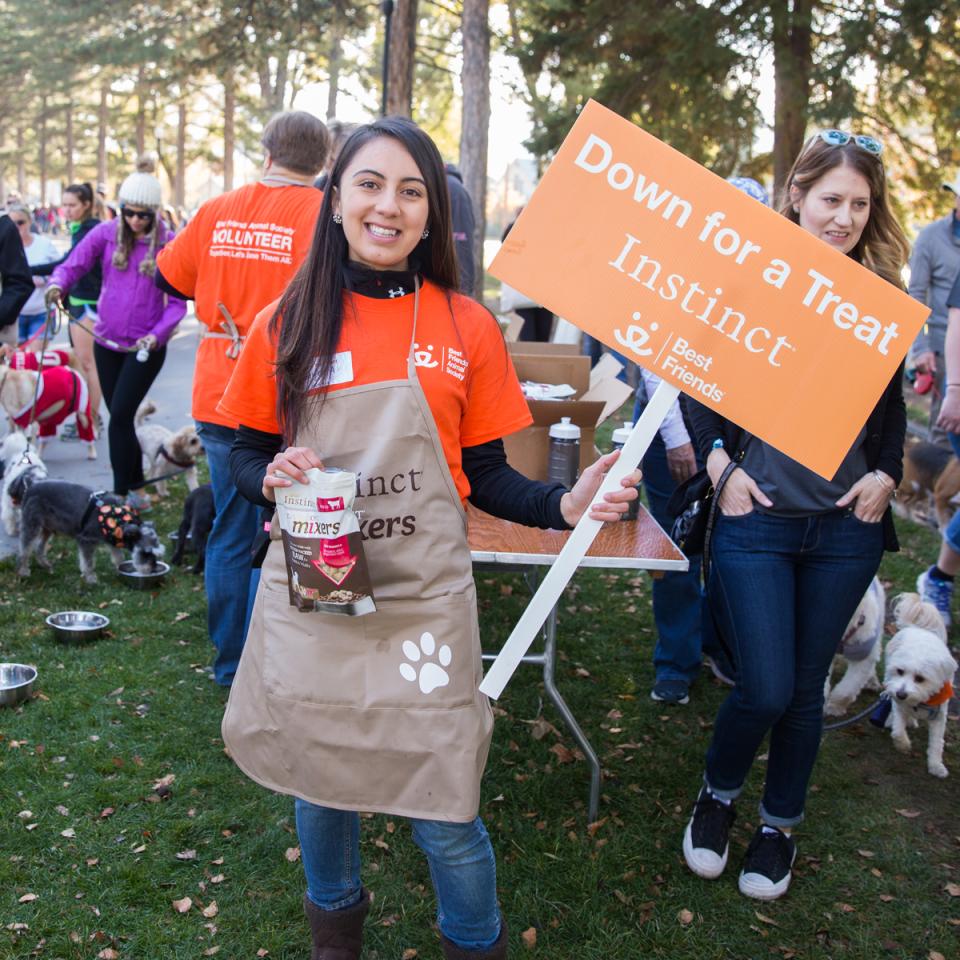 Woman at event holding bag of treats and sign