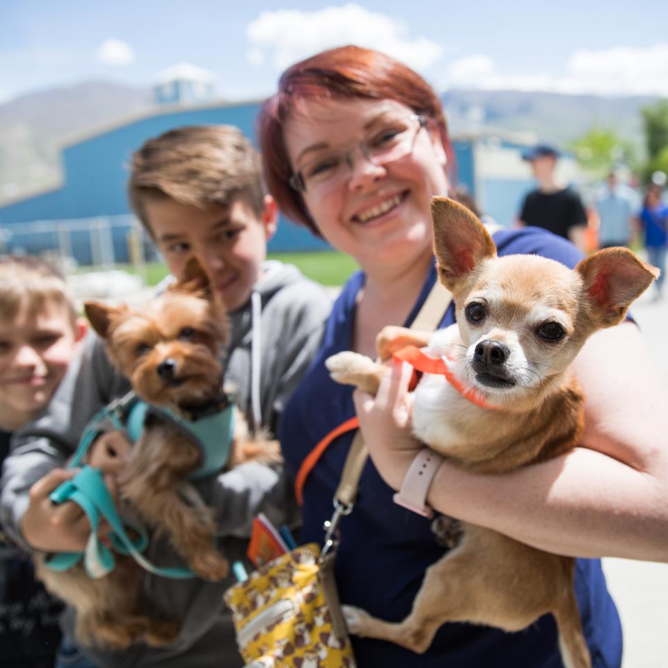 Woman and two kids holding small dogs at event 
