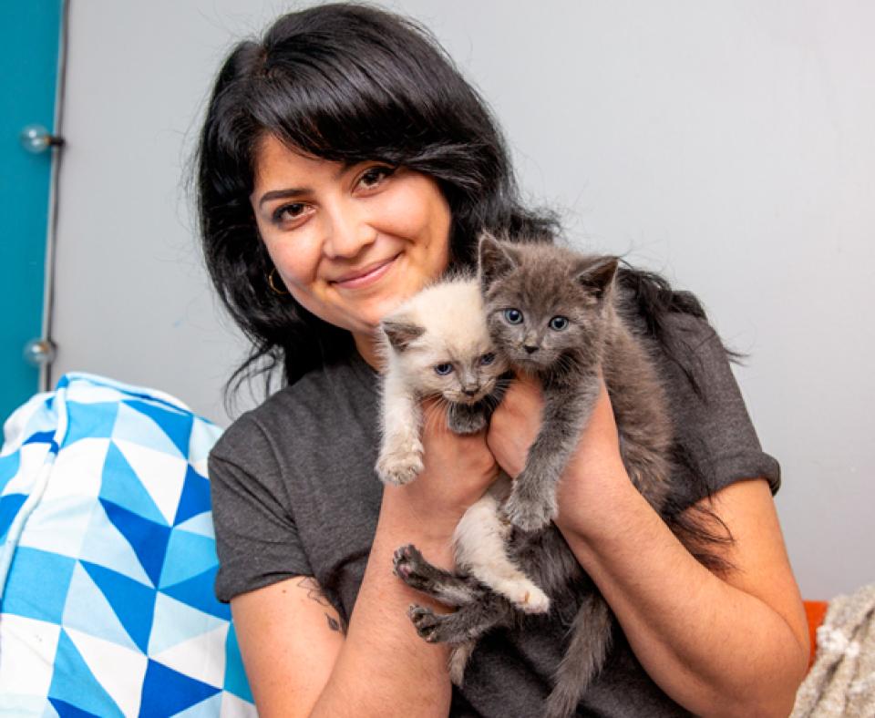 Smiling person holding two kittens