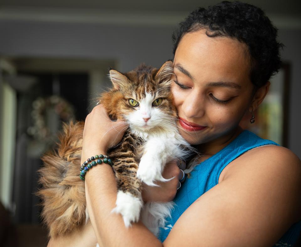 Person cradling a brown and white tabby cat in her arms