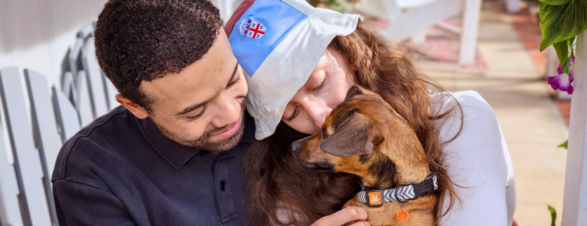 Image of man and woman cuddling with a foster dog