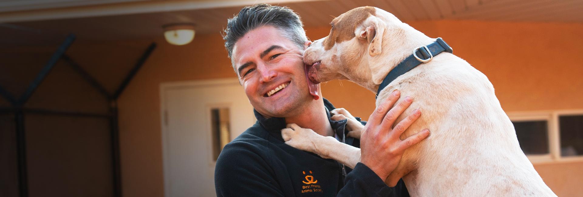 dog licking face of smiling man