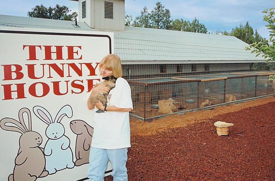 Woman holding bunny next to Bunny House sign