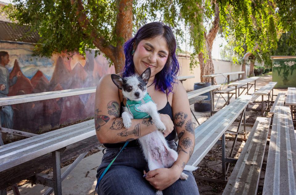 Smiling person holding a small dog in their arms while sitting outside
