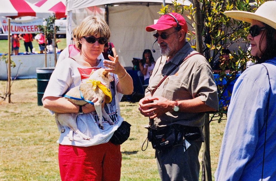 Woman holding small dog and talking with man at adoption event