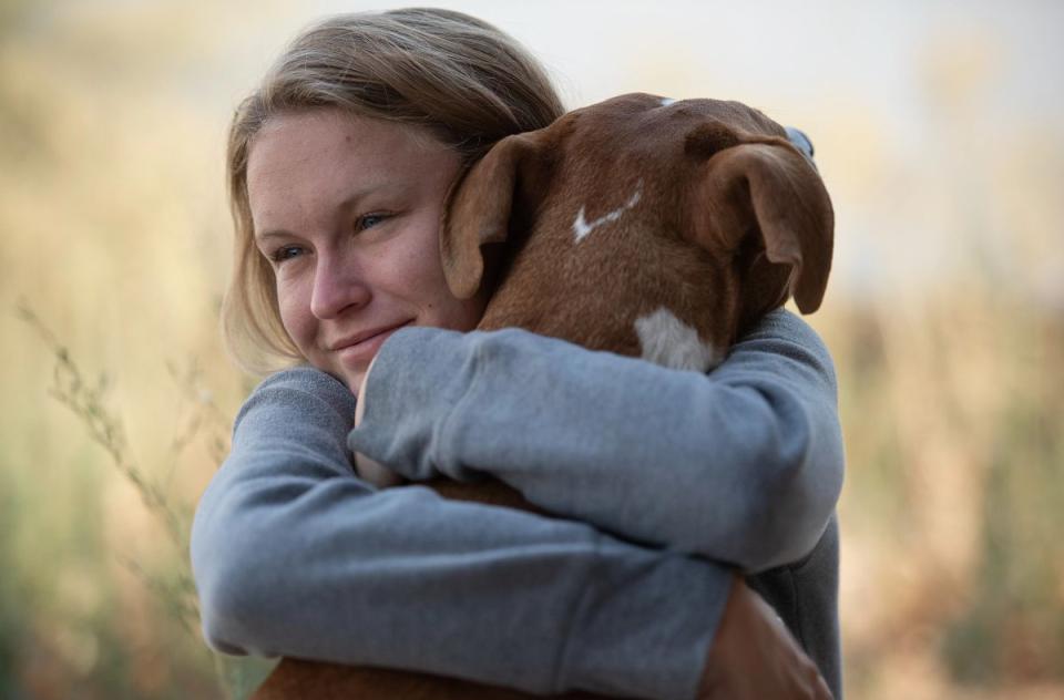 Woman hugging dog in a field.