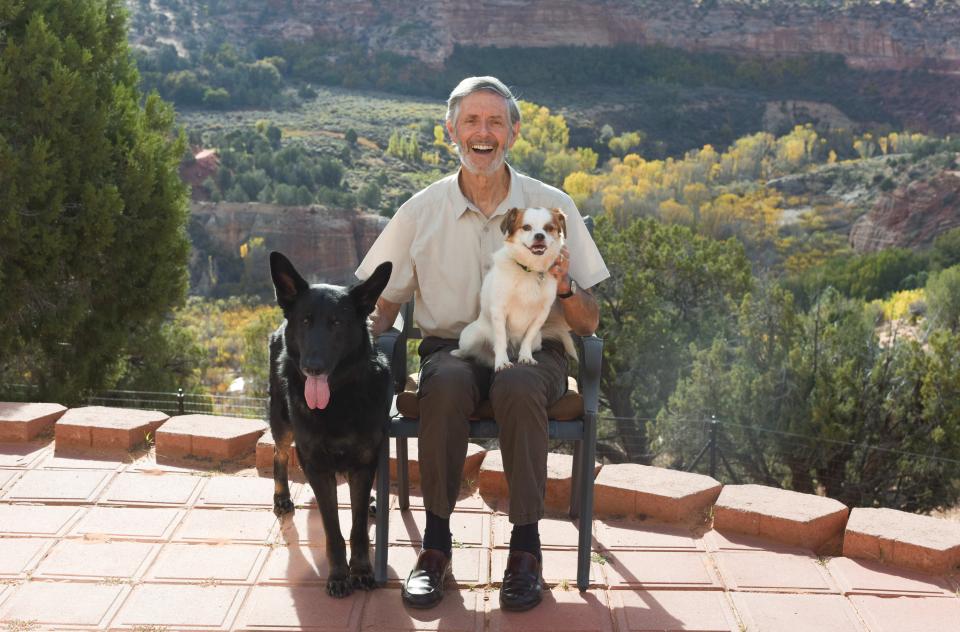 Gregory Castle on a brick patio with a small and large dog, with Angel Canyon at Best Friends Animal Sanctuary in Southern Utah in the background