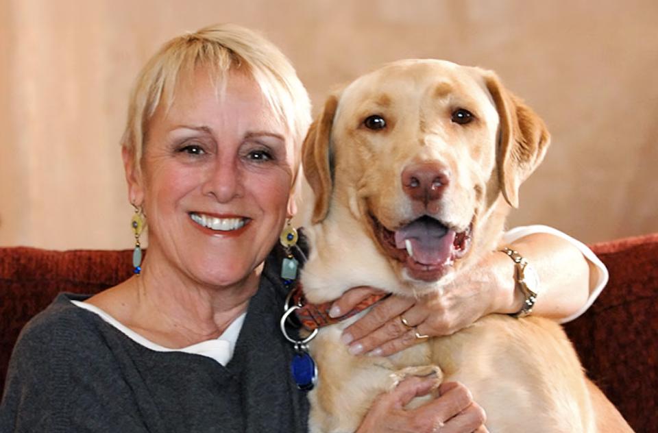 Anne Mejia hugging large brown dog on couch