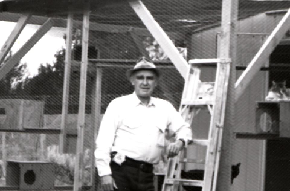 Black and white photo of John Fripp beside some construction of a cat enclosure