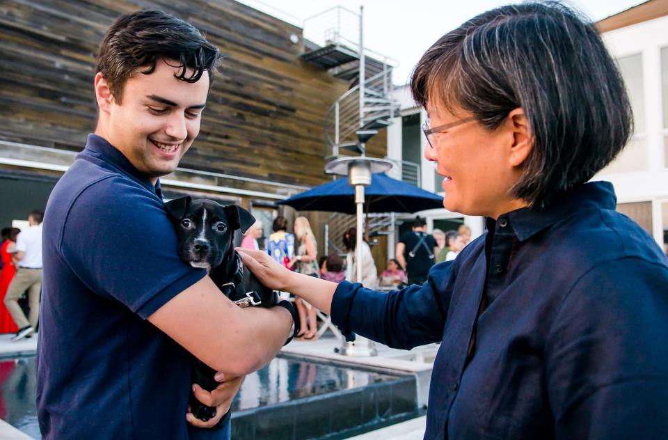 Woman petting black puppy in arms of man at party