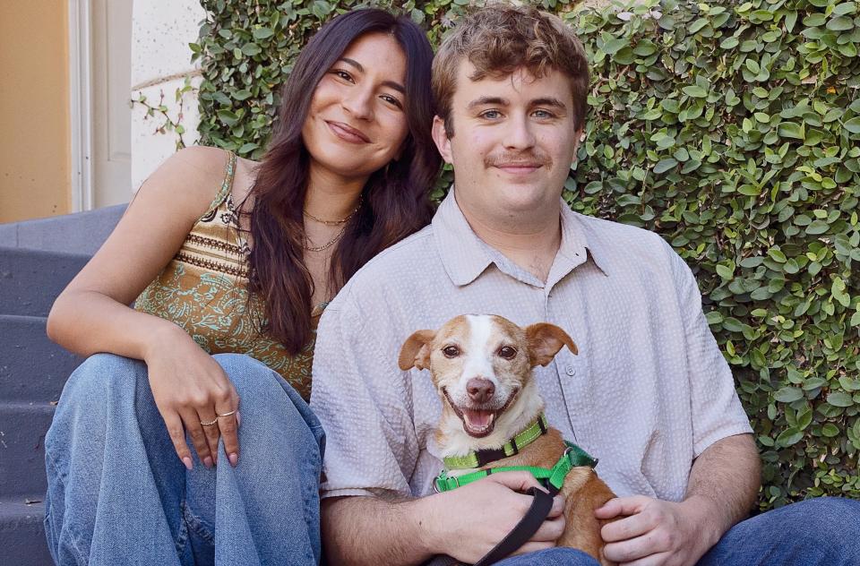 woman and man sitting on steps outside home with small brown and white dog
