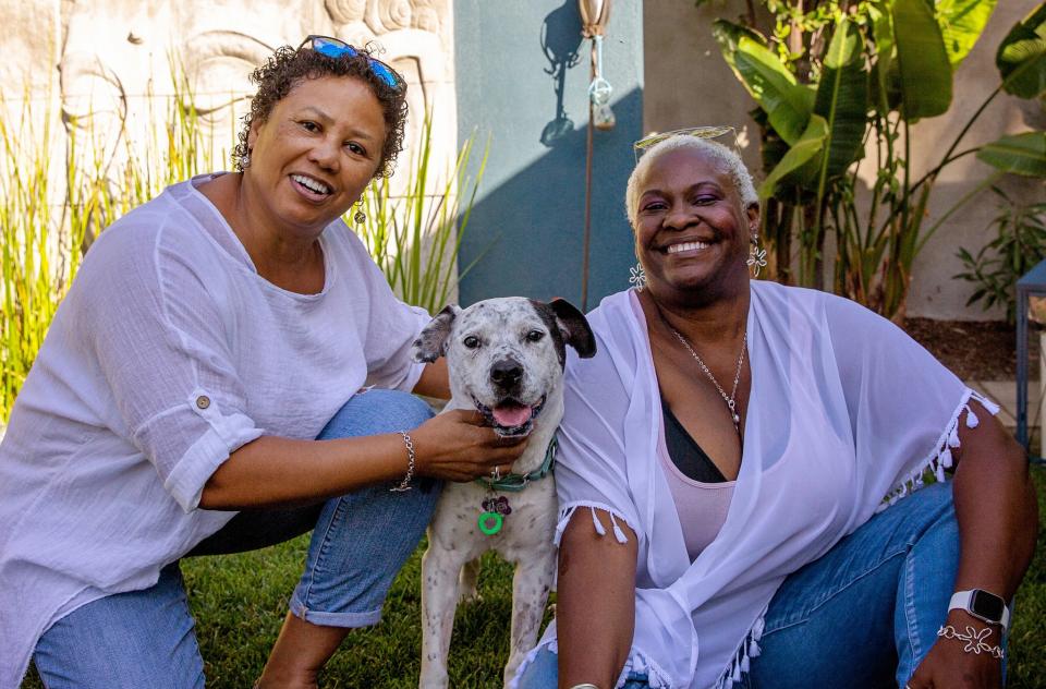 Two people with a dog smiling at the camera