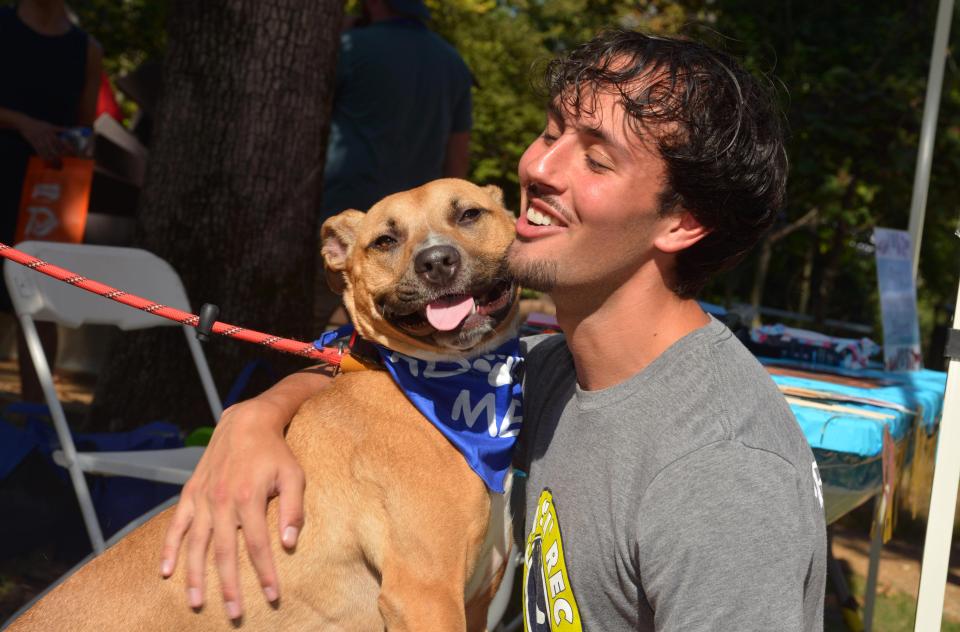Smiling person hugging Cashew the dog, who is also smiling