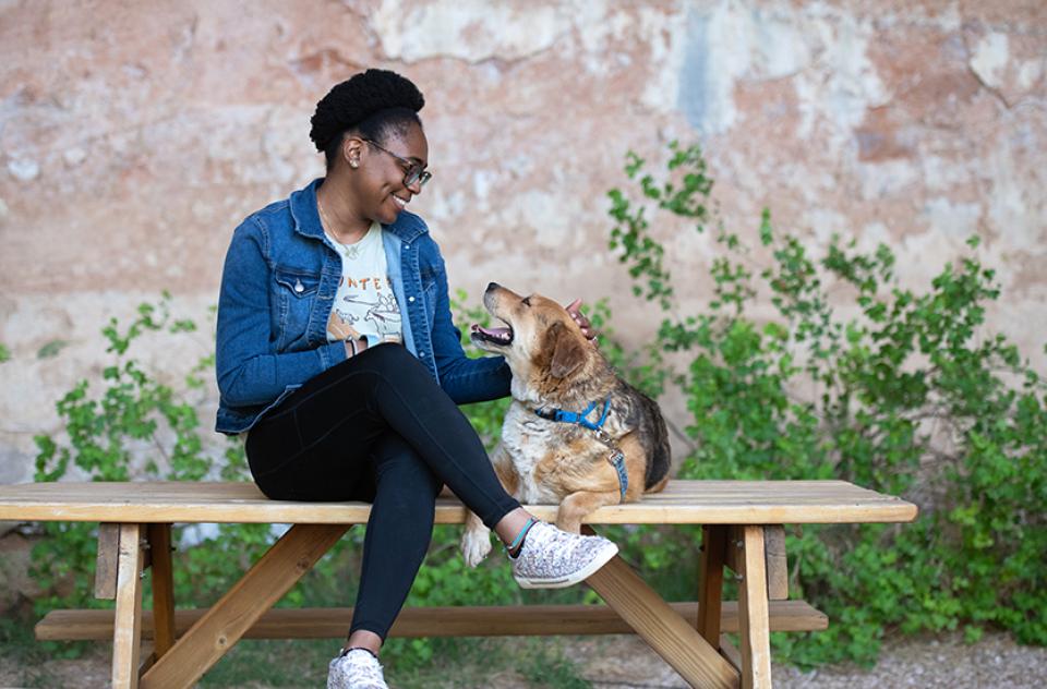 Person wearing BOBS® from Skechers® sitting on a bench beside a dog