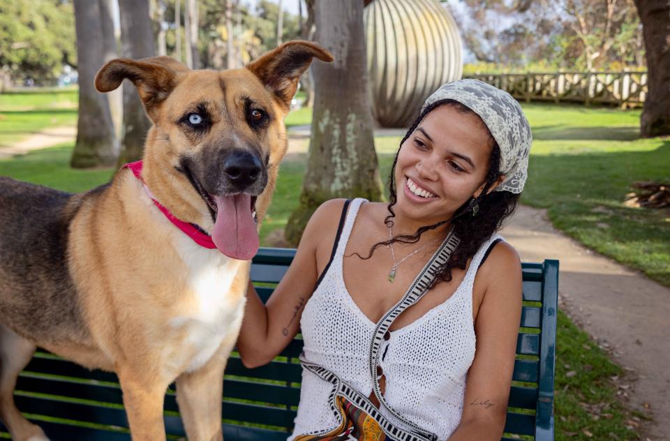 Smiling woman sitting next to a dog on a bench