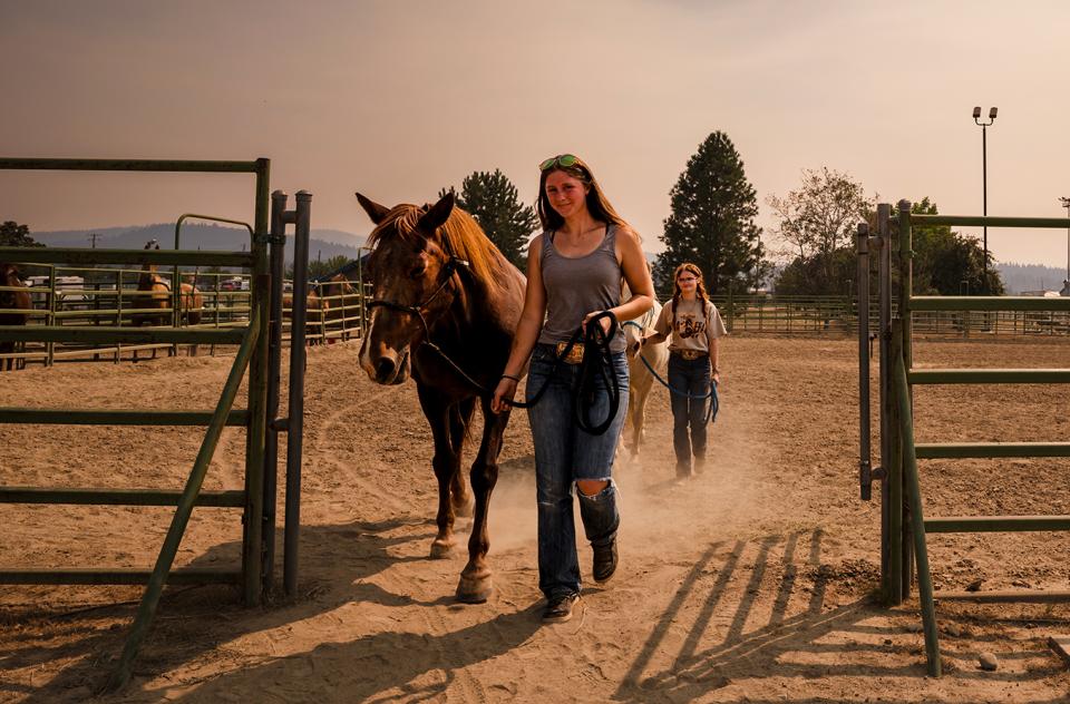 People leading horses at the Spokane County Fairgrounds evacuation facility