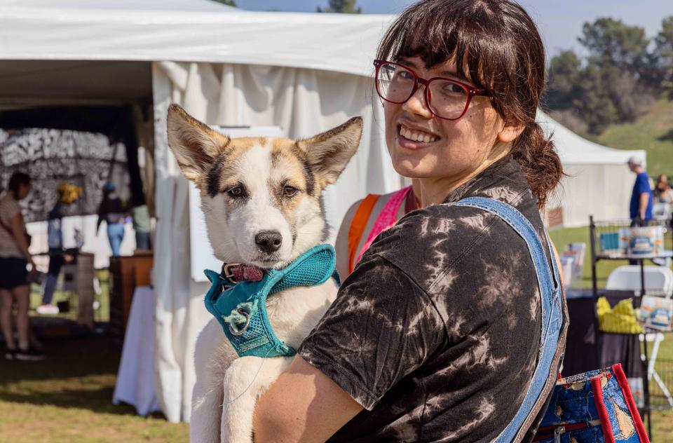 Woman holding a white and tan dog smiling