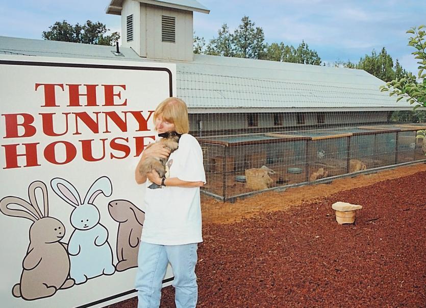 Woman holding bunny next to Bunny House sign