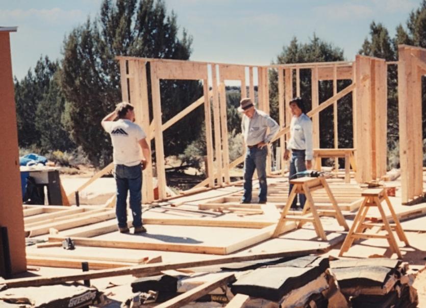 old photo of 3 people and building construction 