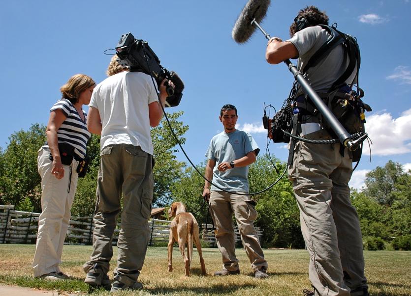 Film crew with trainer and dog in field