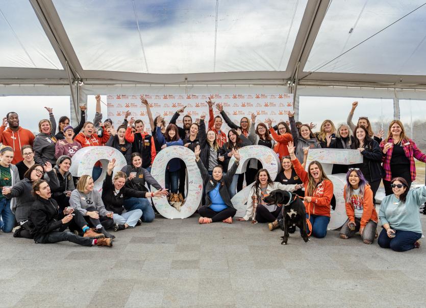 Group of people celebrating by a large statue displaying the number 2025