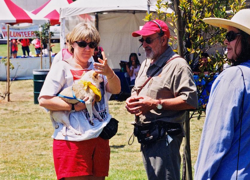 Woman holding small dog and talking with man at adoption event