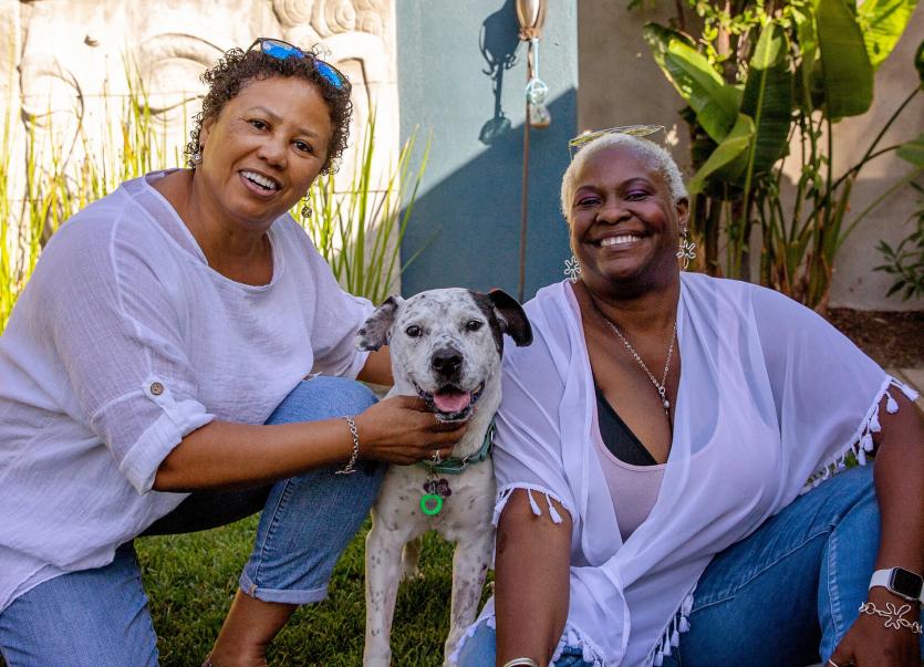 Two people with a dog smiling at the camera
