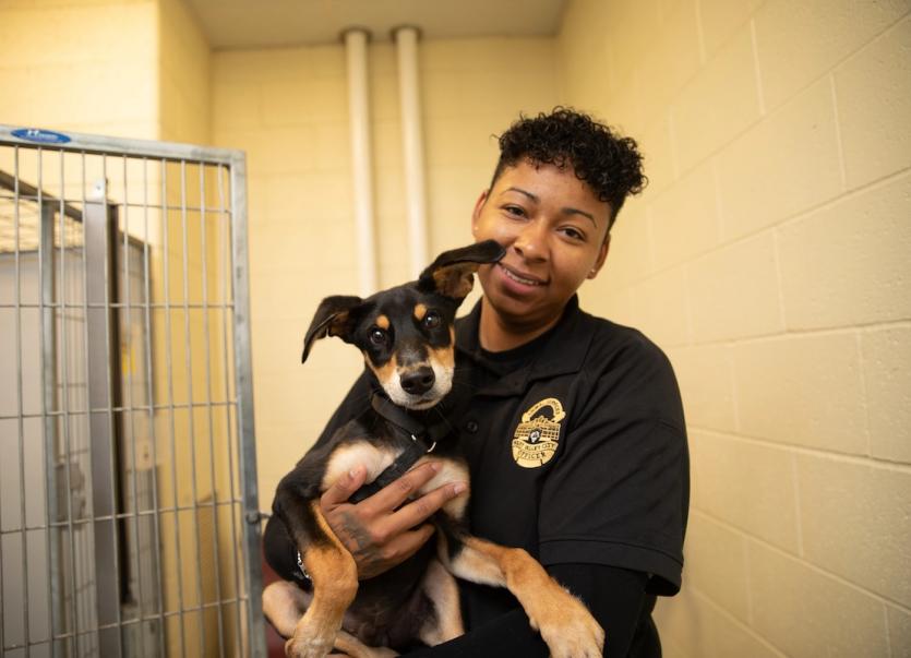 Black female ACO holding a black and brown dog