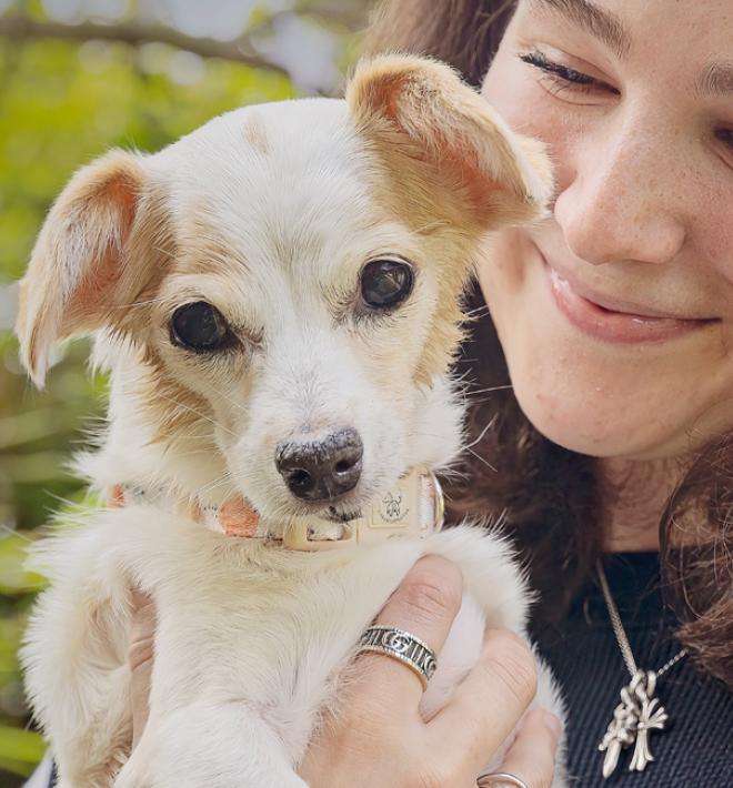 Smiling person holding a small white dog