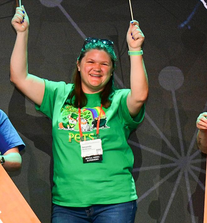 People on stage at the Best Friends National Conference holding flags and banners