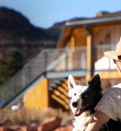 woman in hat carrying a dog