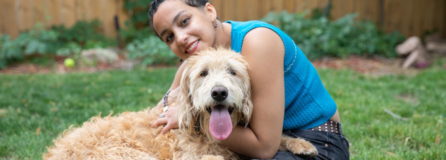 Woman sitting in yard with fluffy brown dog
