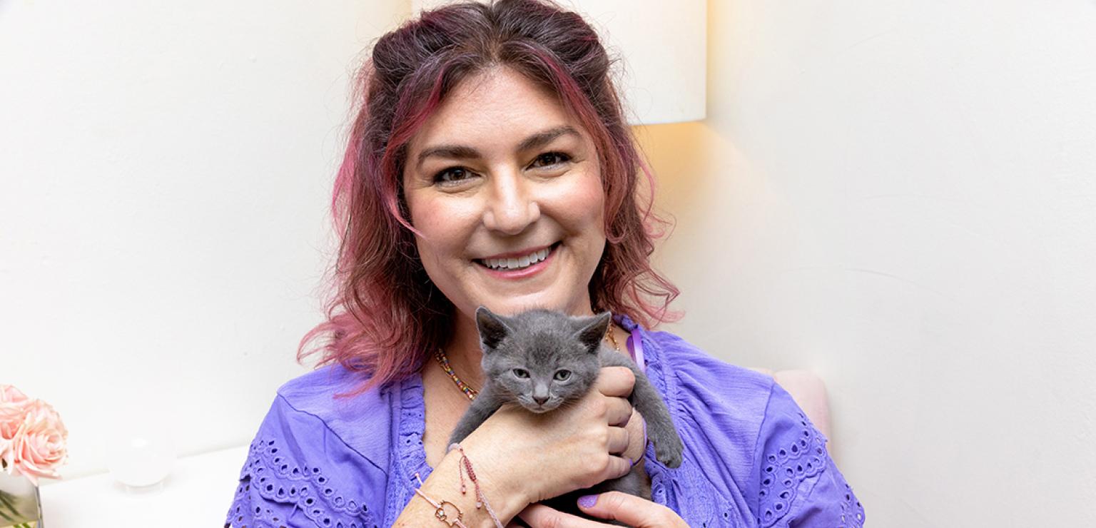 Smiling person holding a small gray kitten