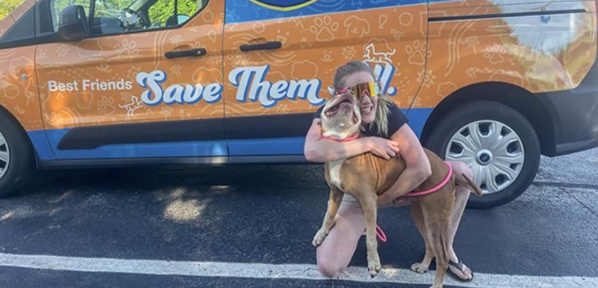 Captain the dog being hugged in front of the Best Friends transport van