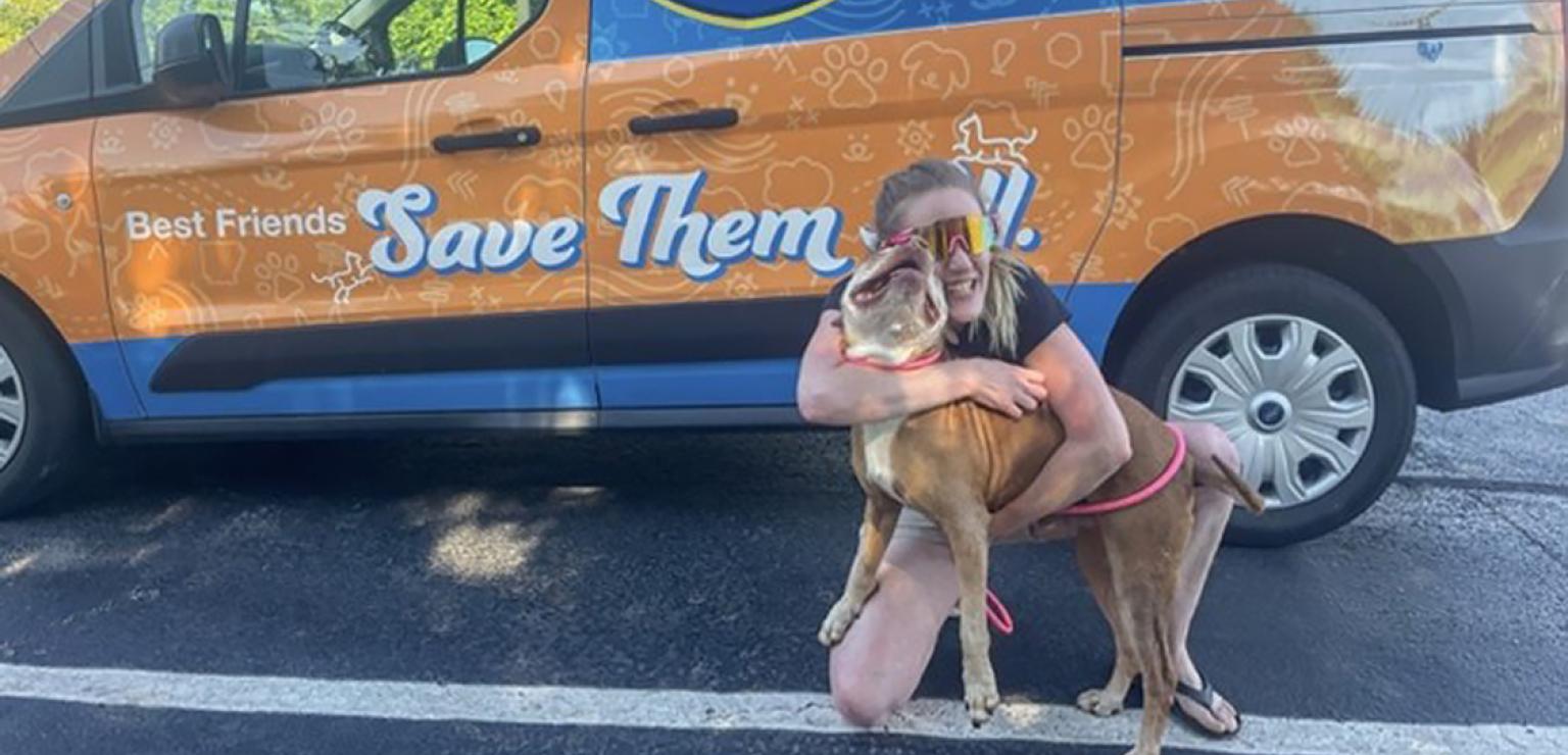 Captain the dog being hugged in front of the Best Friends transport van
