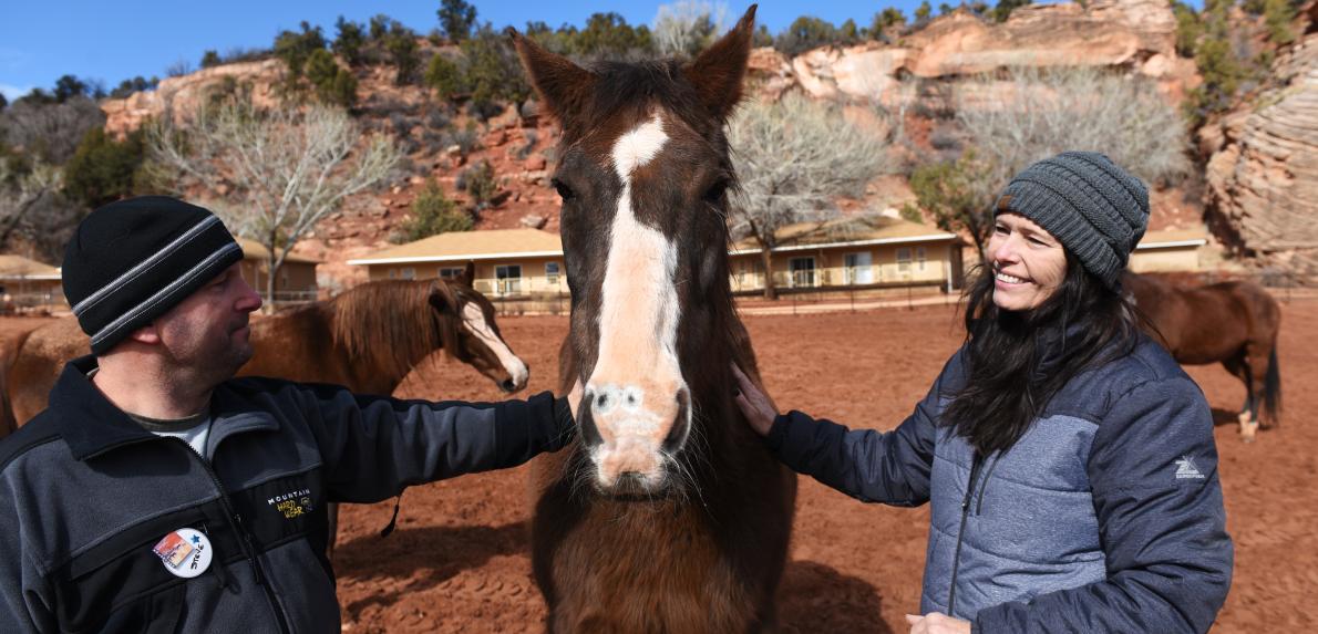 Two volunteers outside in a pasture with a horse